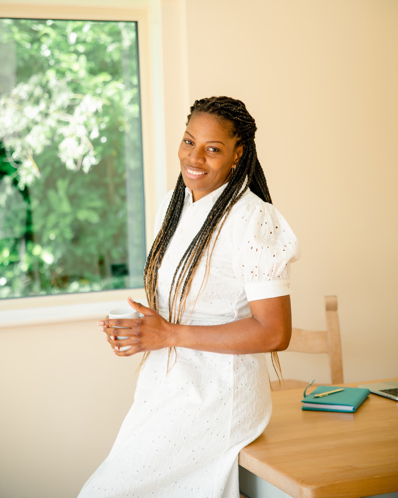 Alison Eastick, founder of SheVive, smiling while holding a cup in a bright home office